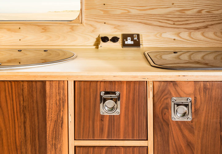 Campervan integrated cabinet system with wooden workdesk, shelving and cabinet system.