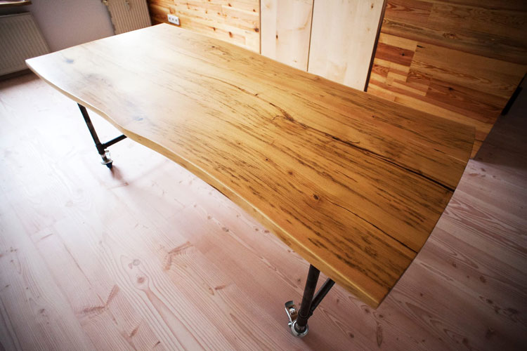 Broad wooden board table with metal legs on wheels. Rustic design. Bird view. Focus on natural wood pattern design.